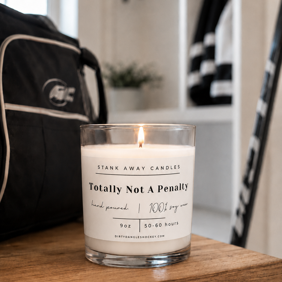 A white scented hockey candle on a wooden bench with hockey gear. Totally not a penalty