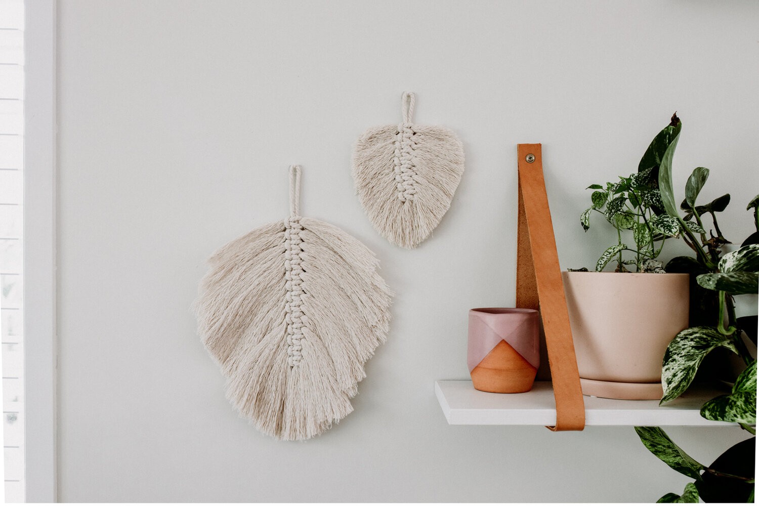 Large and small macrame leaves hang on the wall.