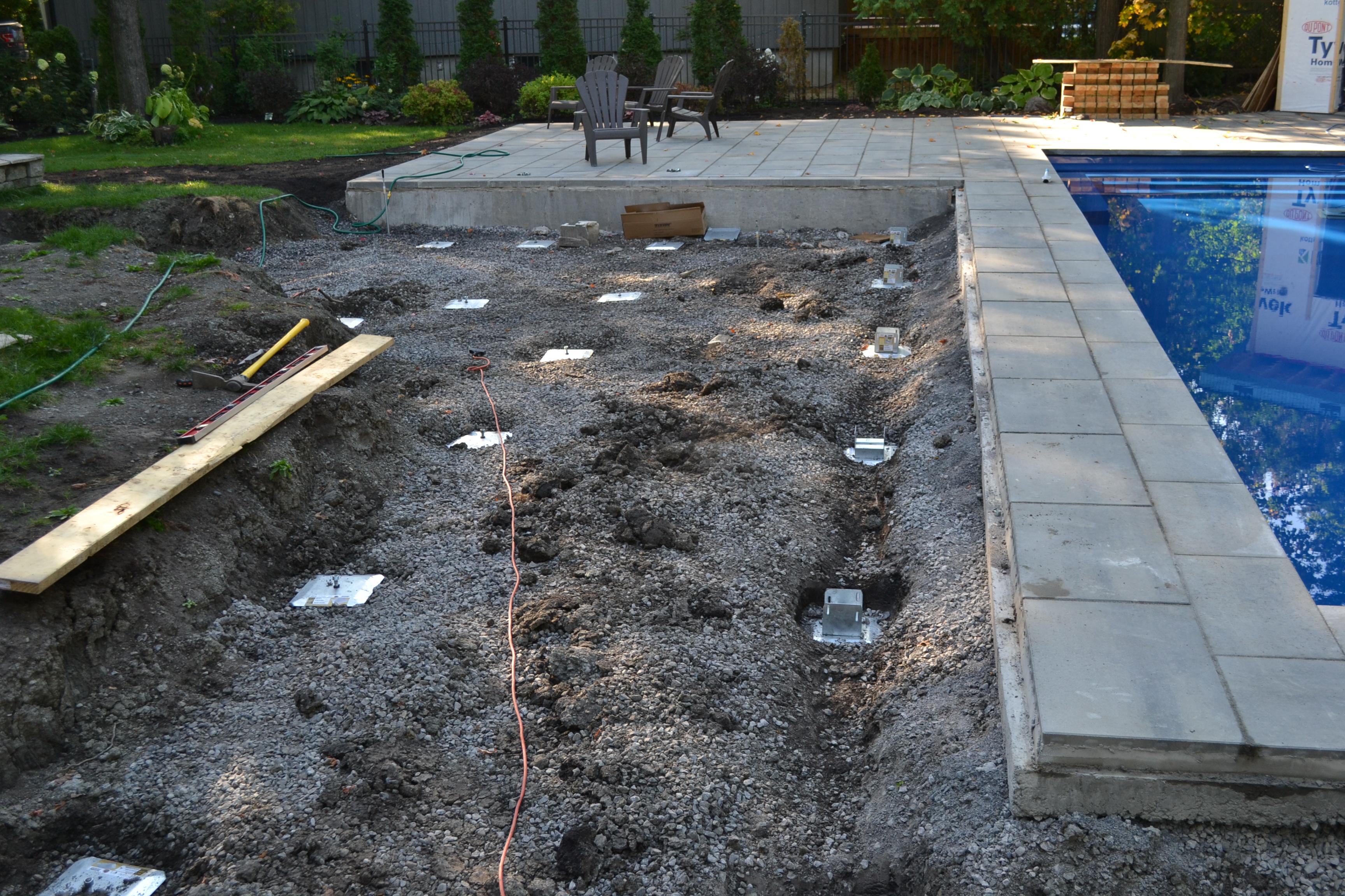 deck foot anchors installed with an impact wrench into excavated poolside soil