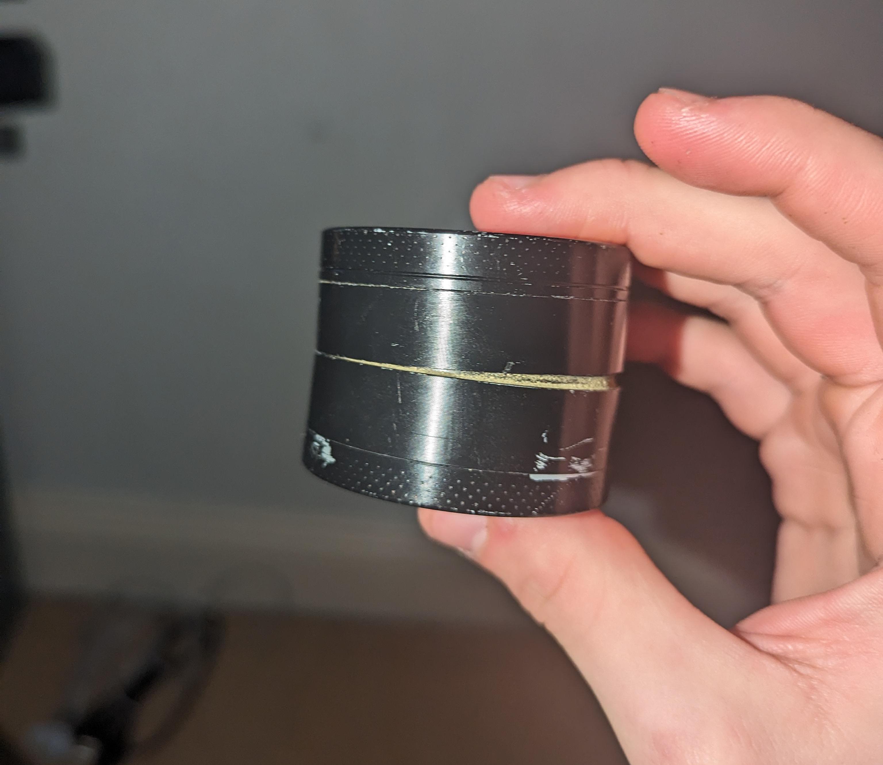 A "joint locked" non-Prism herb grinder stuck shut from resin buildup, illustrating why the Prism Herb Grinder’s friction-reducing glide ring is superior for preventing sticky lids and jamming.