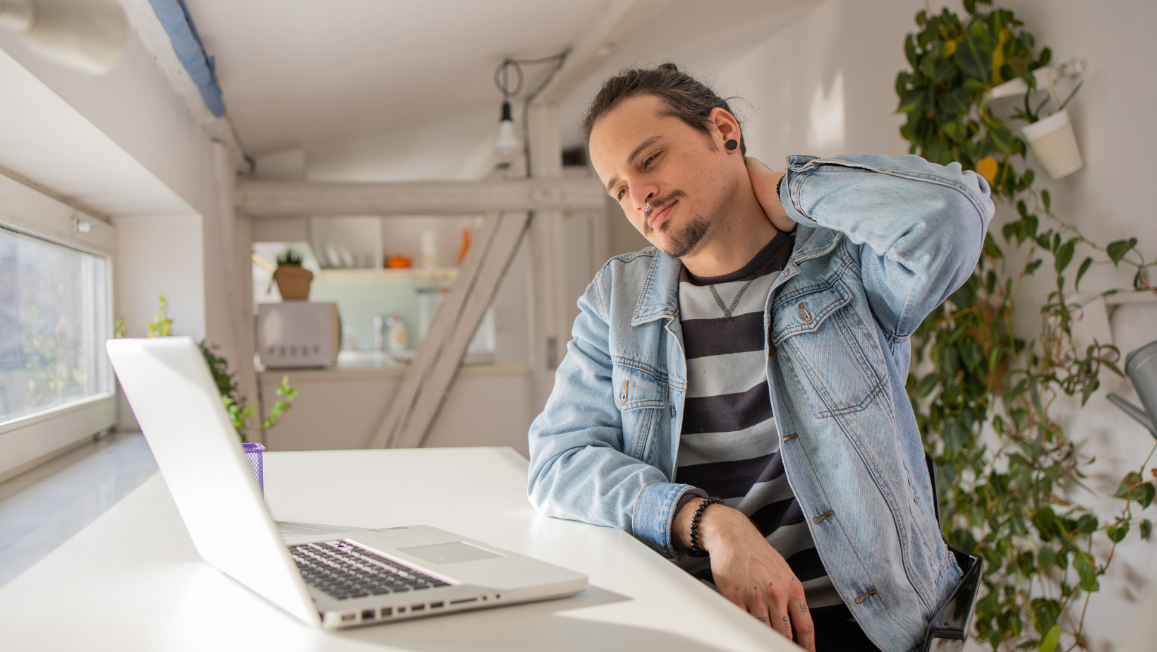 Man working from home rubbing his stiff neck