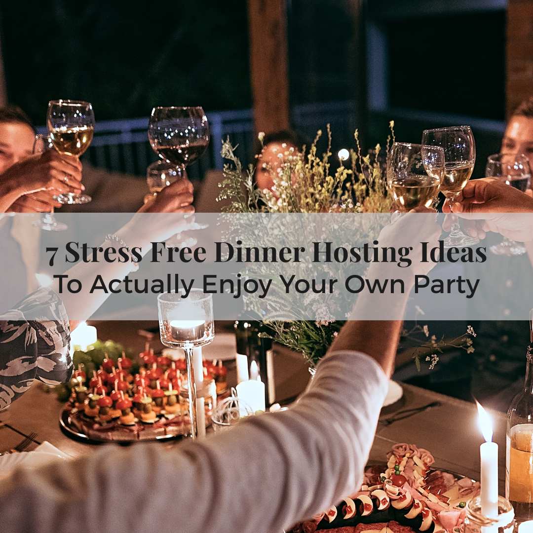 A group of friends raise their glasses in a warm, candlelit toast around a beautifully set dinner table with appetizers and flowers, representing a joyful and stress free dinner hosting experience.