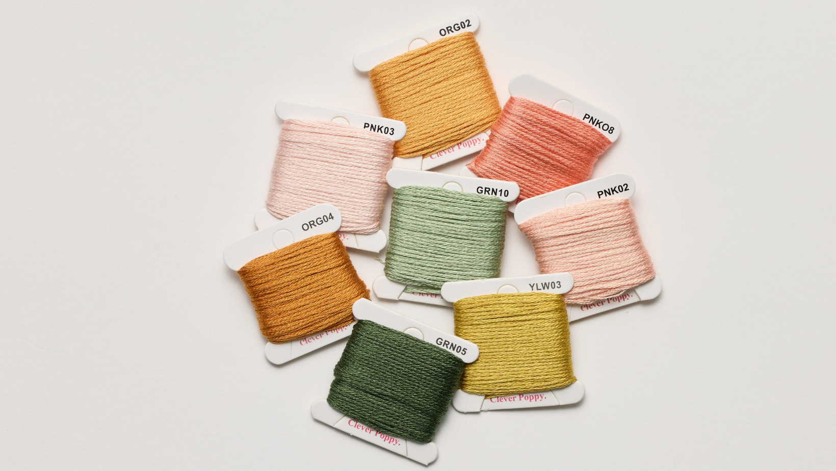 Eight cards of Clever Poppy embroidery floss in fall shades of orange, pink, green and yellow.
