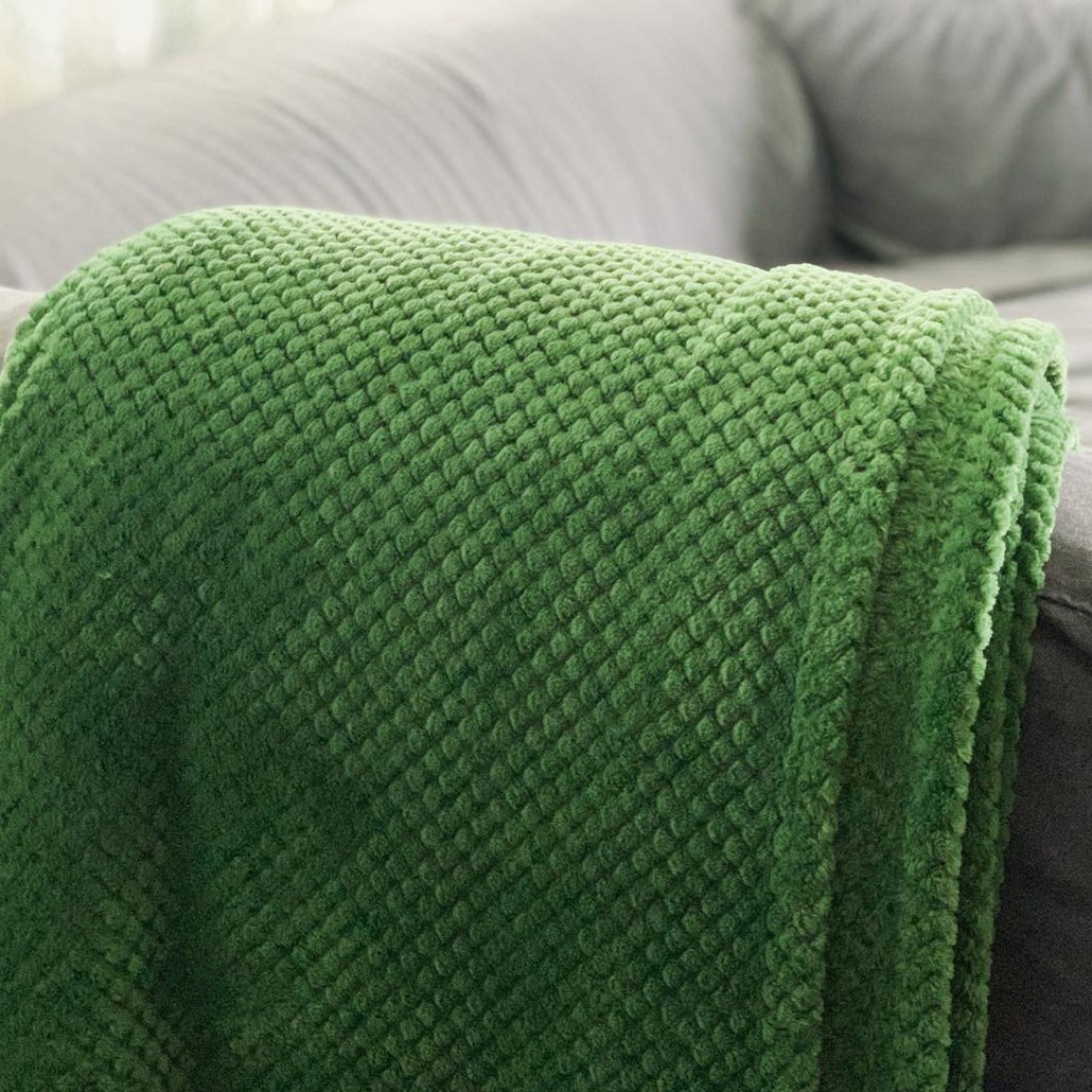picture of a dark green blanket draped over the arm of a couch