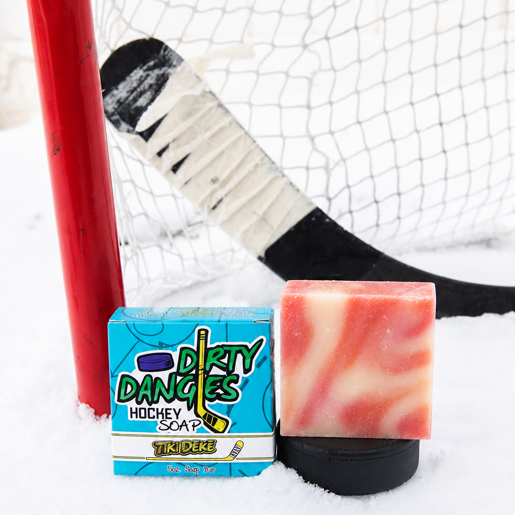 a pink, orange and white bar of tiki deke tropical coconut girls hockey soap on a snowy background with a hockey stick and hockey goal.