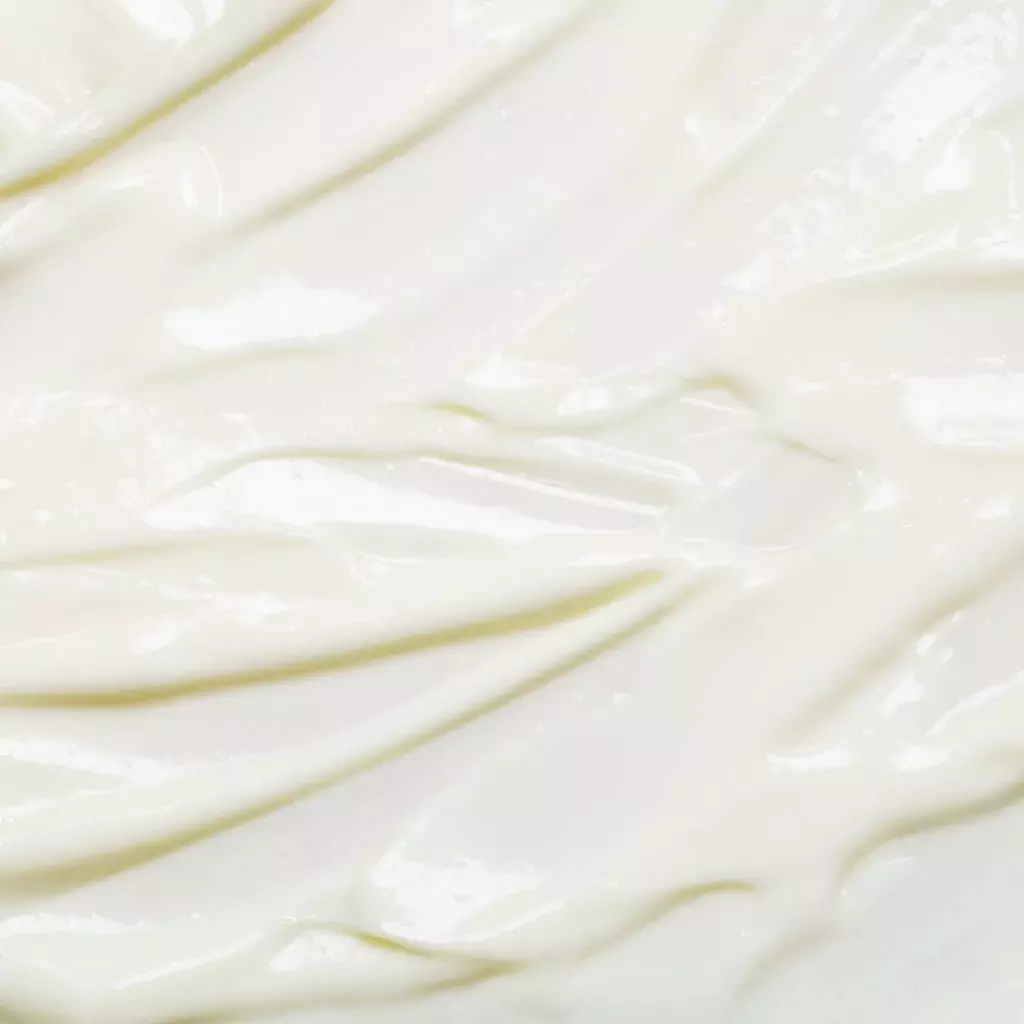 Close-up della texture di una crema bianca spalmata, che mostra la sua consistenza liscia e ricca