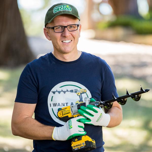 Brian holding a drill with a Power Planter bit in a garden.