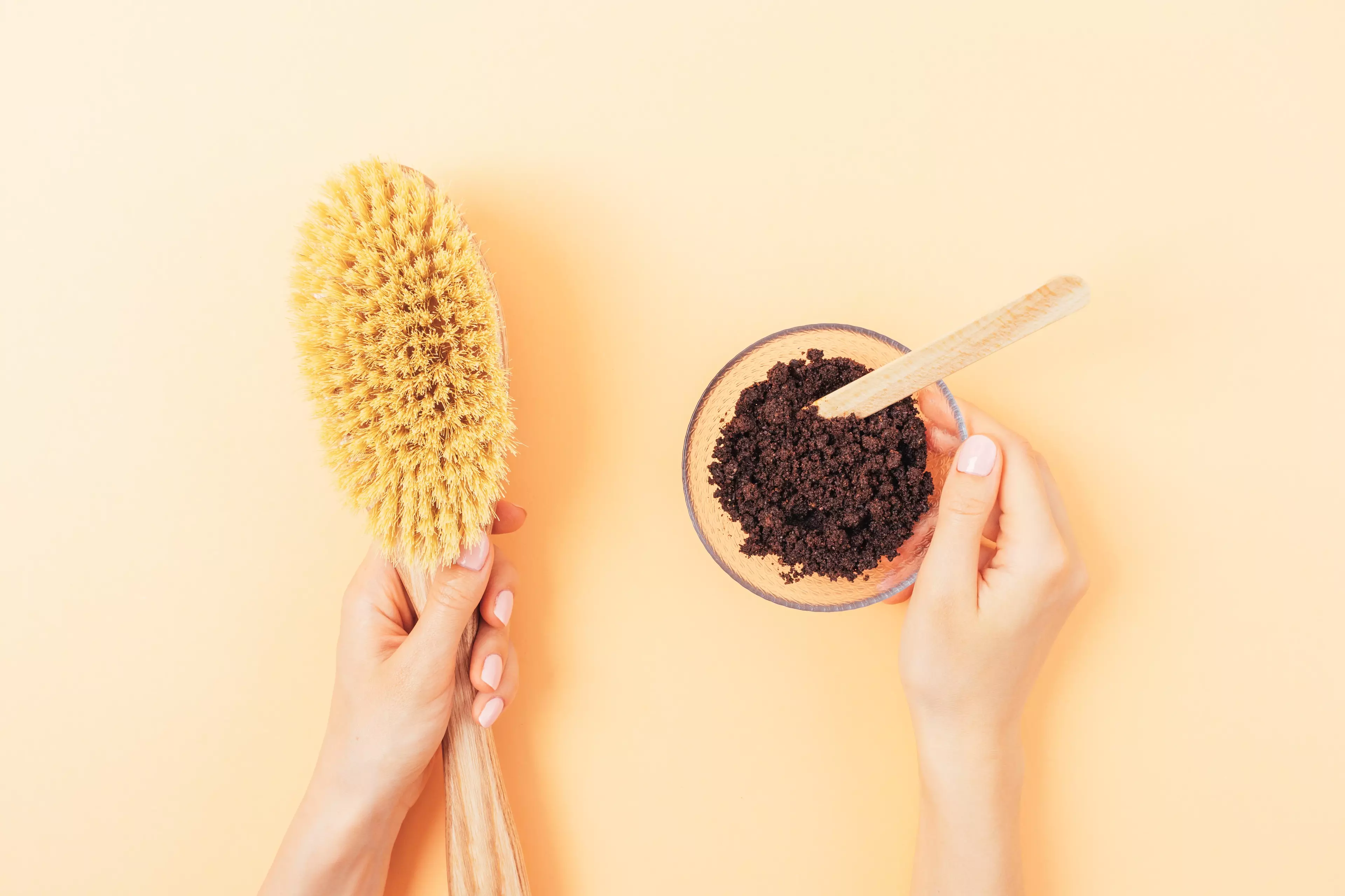 Coffee grounds scrub being massaged onto a hand on a spa-style counter with towel, honey and coffee beans.