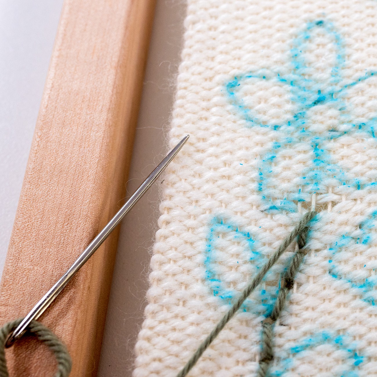 An embroidered bit of weaving is pulled too tight, exposing a gap in the wool.