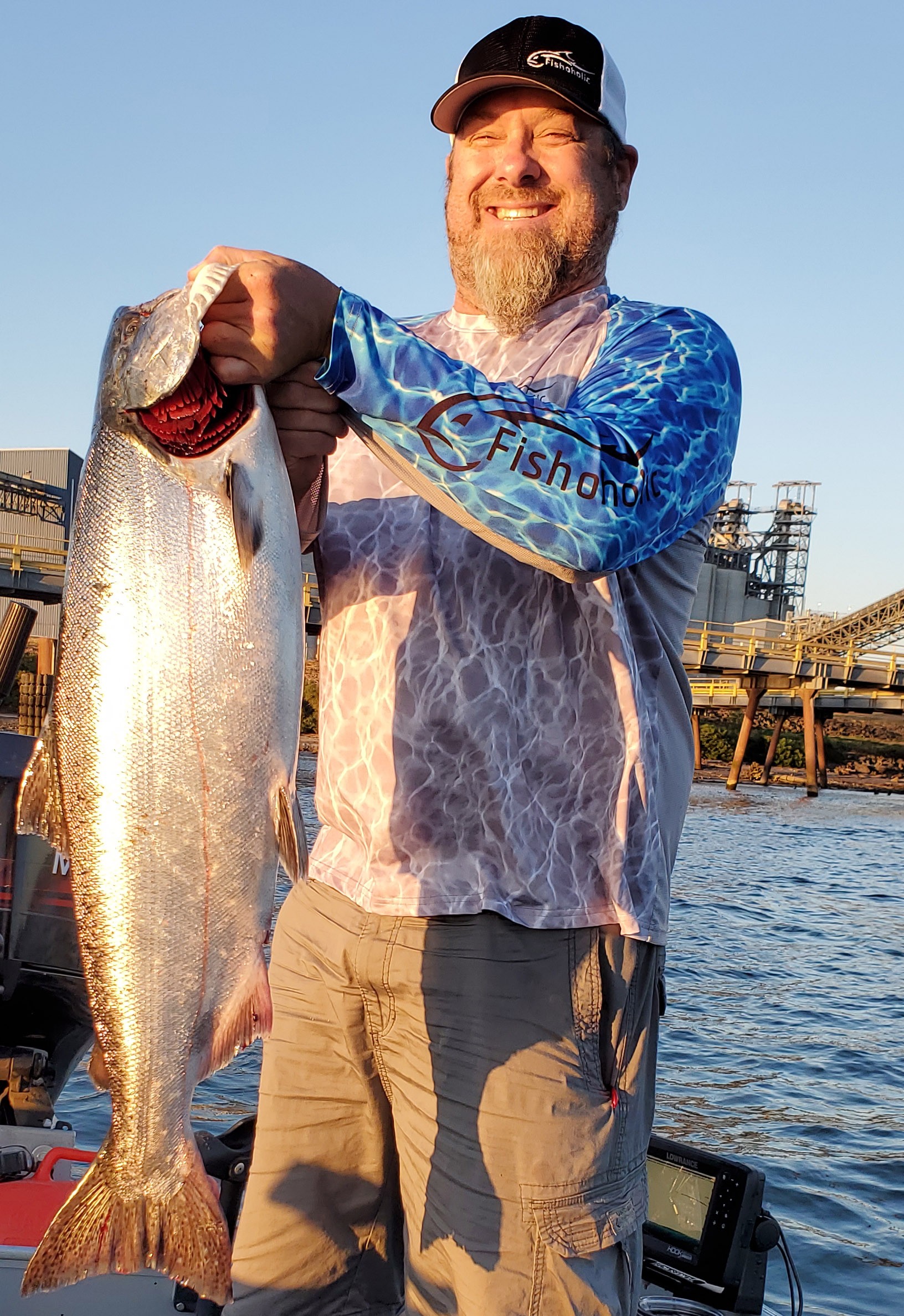 Man holding up a large fish wearing Fishoholic fishing shirt