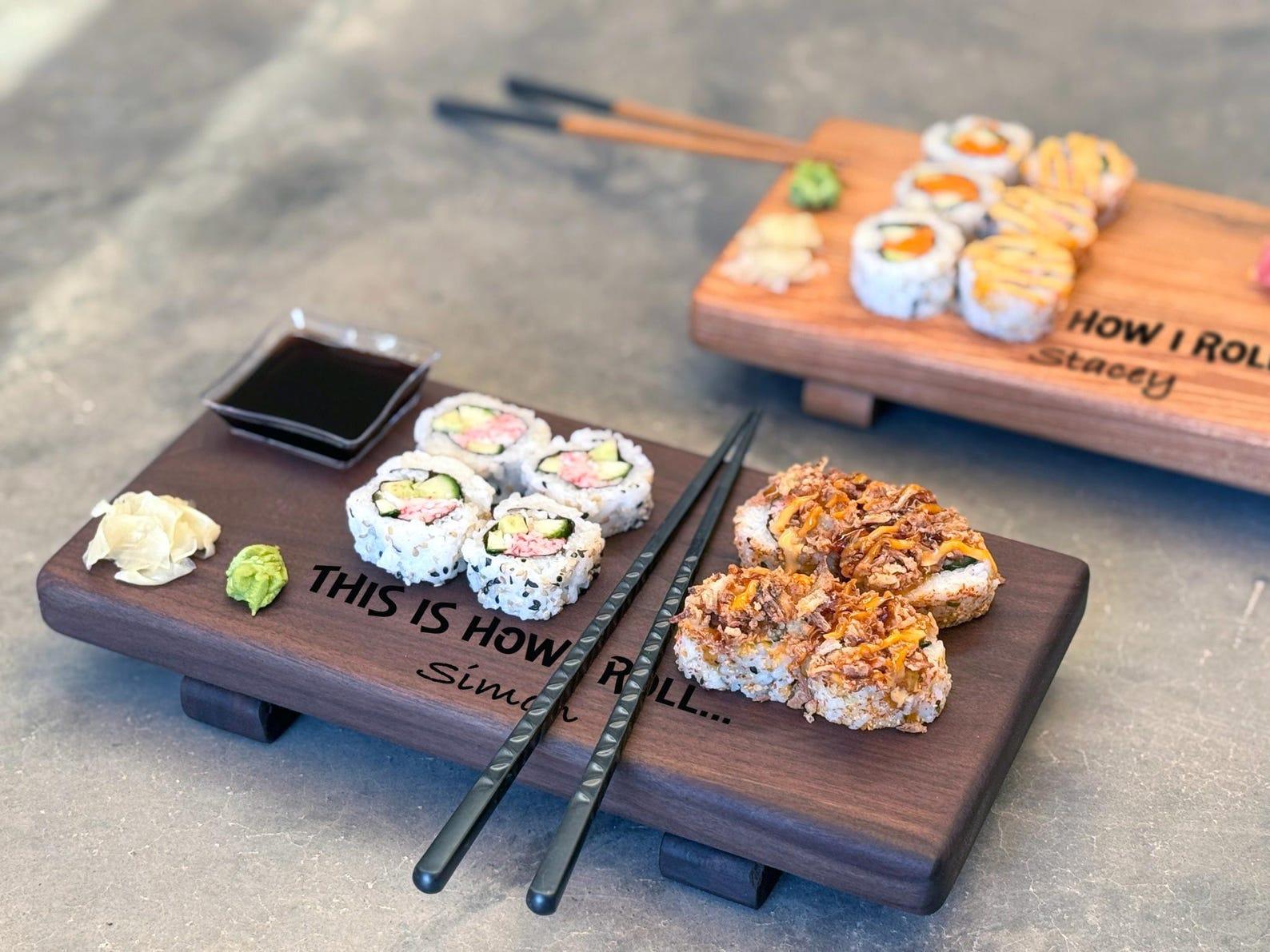 two personalized wooden sushi boards with food on them and chopsticks