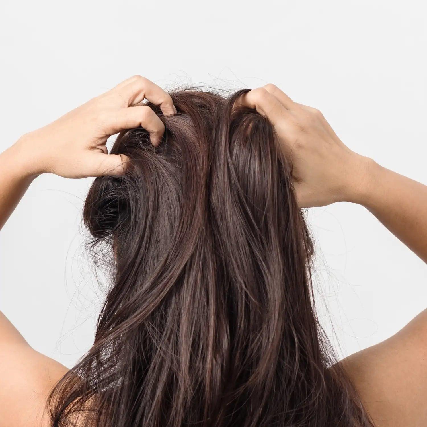 woman applying rosemary oil to her scalp