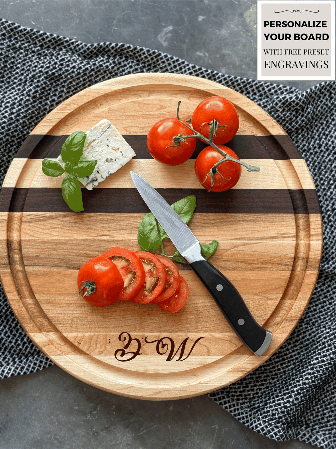 Round wooden edge grain cutting board with maple & walnut stripes, personalized engraving, & a juice groove. Topped with fresh tomatoes, basil and cheese, showcasing a stylish and functional serving or prep piece. Perfect for entertaining or gifting.