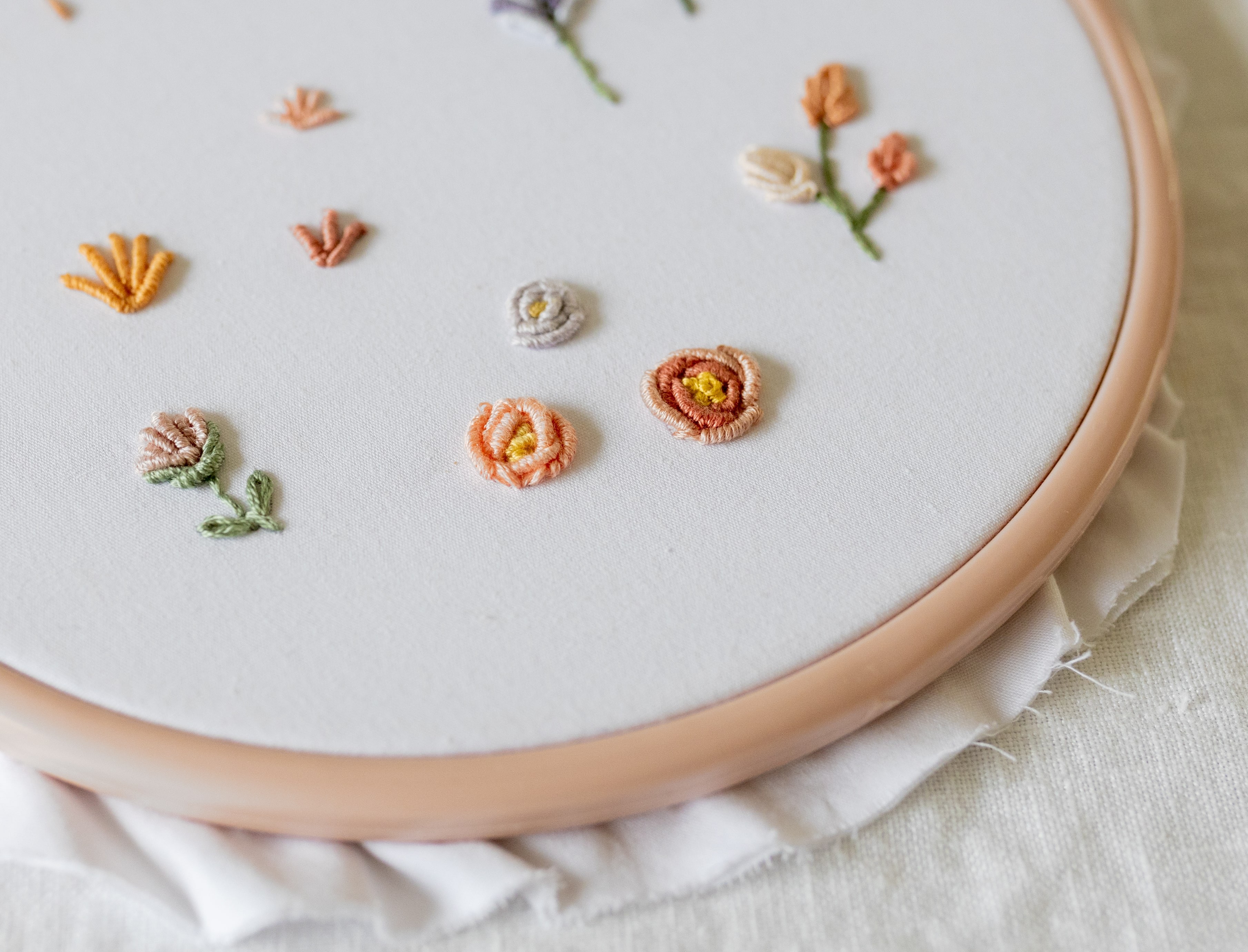 Various flowers made with Bullion Knots are stitched on an embroidery hoop.