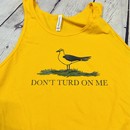 Picture of a gold and yellow men's tank top with a picture of a seagull standing in the grass. Text on the men's tank top says "Don't Turd On Me." Similar to the Gadsden "Dont Tread On Me" Flag