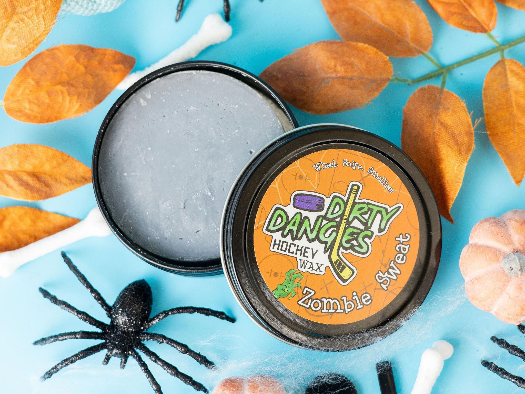 A tin of Halloween dirty dangles hockey zombie sweat pumpkin spice stick wax on a spooky background with spiders and pumpkins