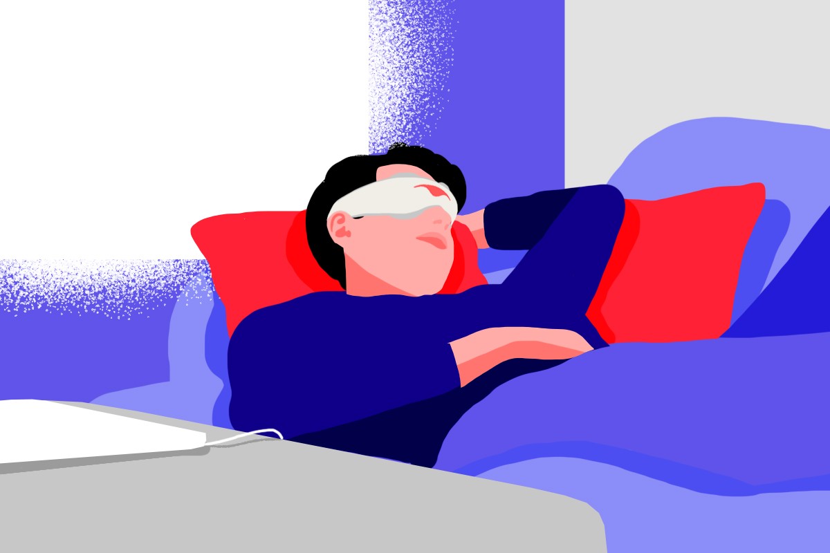 A man taking his daily nap on a couch, wearing a gray sleep mask with eye cups