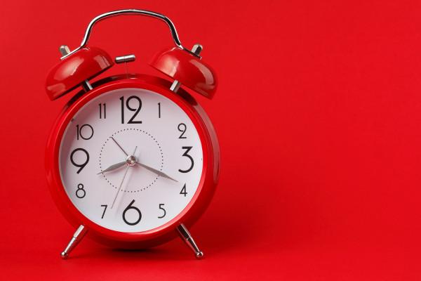 Analog clock on a bright red background.