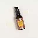A bottle of Prinourish kept on a light color background with droops of serum around it