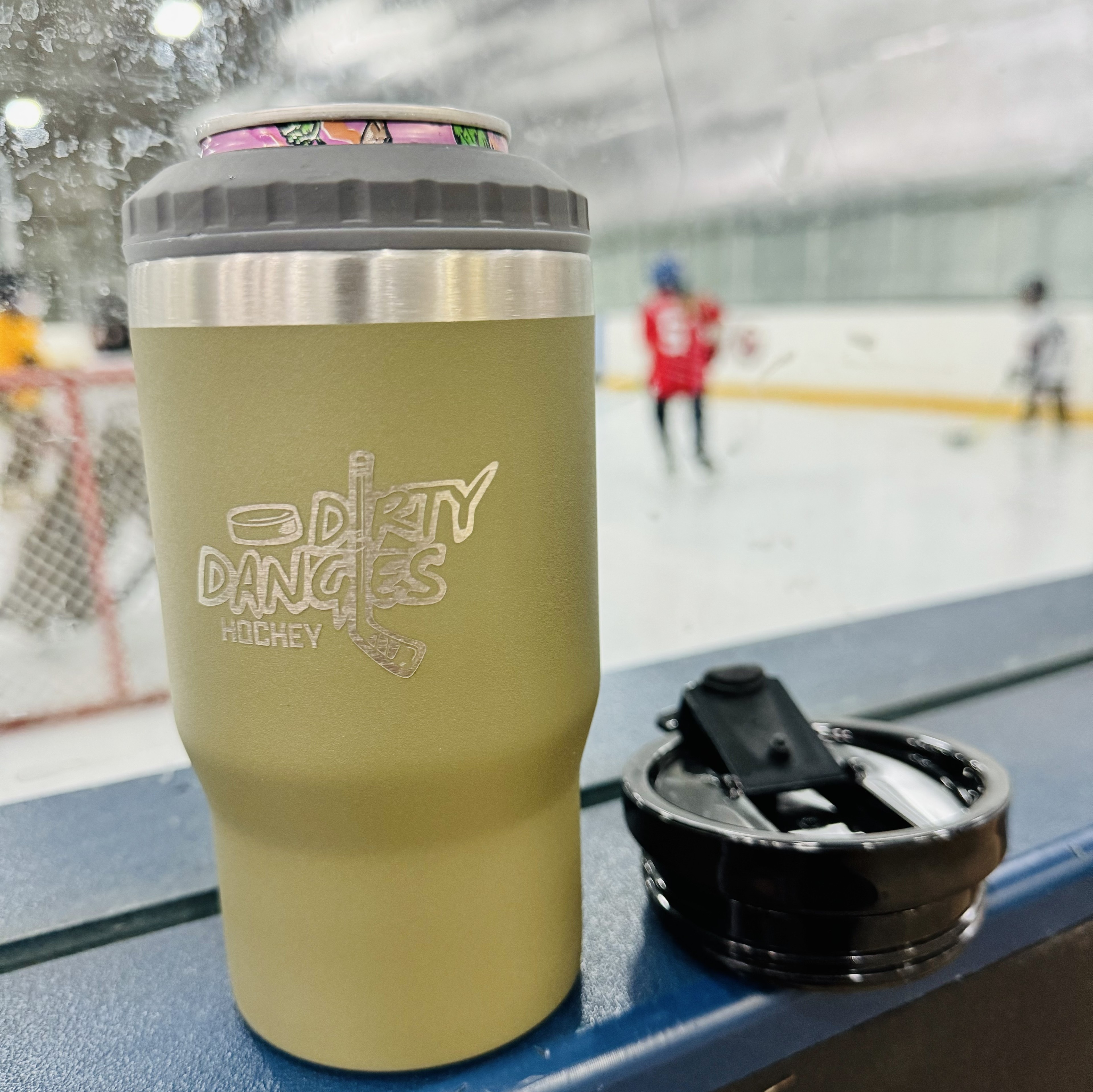 A tactical green dirty dangles 4 in 1 drink tumbler can cooler in an ice rink