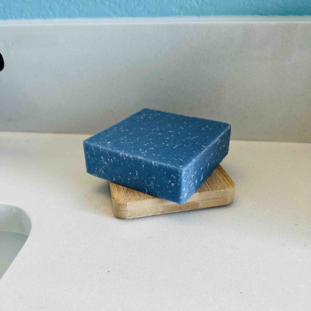a bamboo soap dish sits on a white sink background