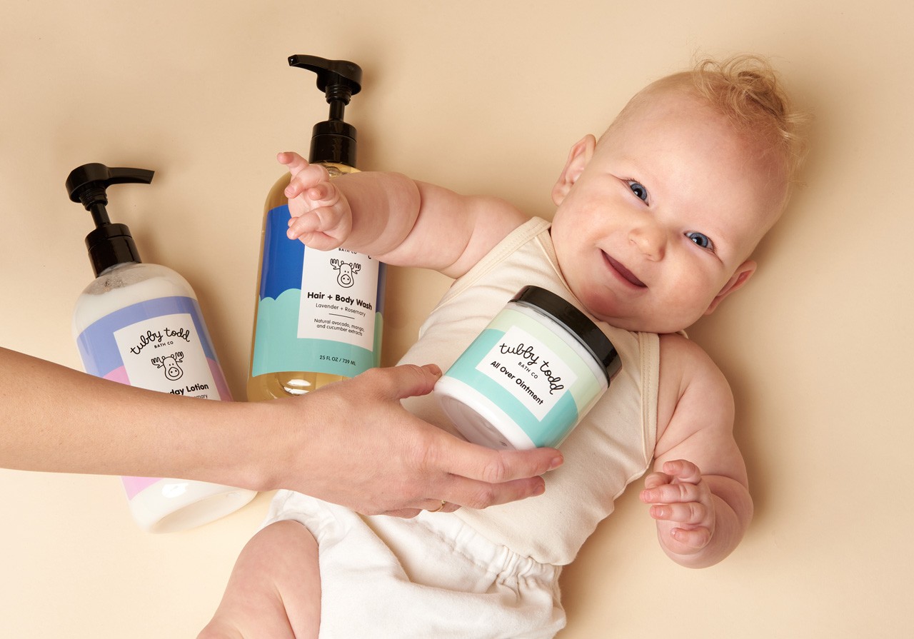 The Regulars Bundle products are on the sink and the baby is standing in front of them.