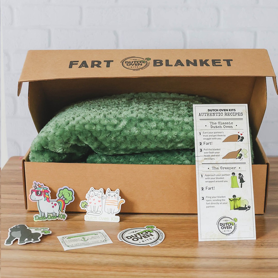 A green dutch oven kit sits on a wood background with a recipe card and stickers. Fart Blanket