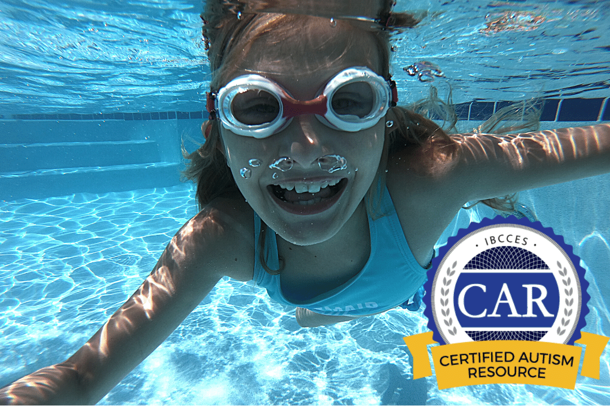 Girl wearing pink Frogglez swimming underwater. Certified Autism Resource badge appears