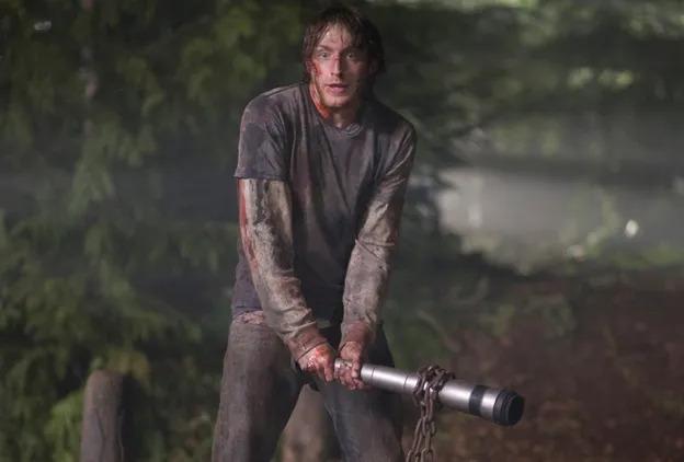 Bloody Marty Mikalski from The Cabin in the Woods standing in the forest, holding his iconic mug pipe as a weapon, symbolizing the "Always Be Perceptive" survival rule.