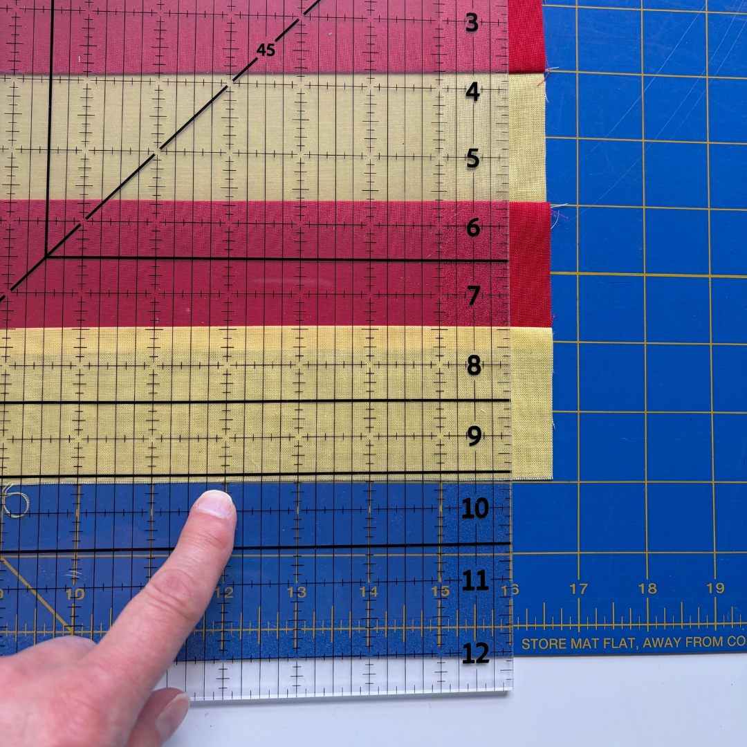 Madam Sew 12.5” Square-Up Ruler on top of a quilt block where the block edge is a little past the 9.5” bold horizontal guideline.