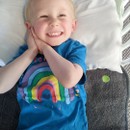 Happy boy lying in bed on grey washable bed mat - PeapodMat