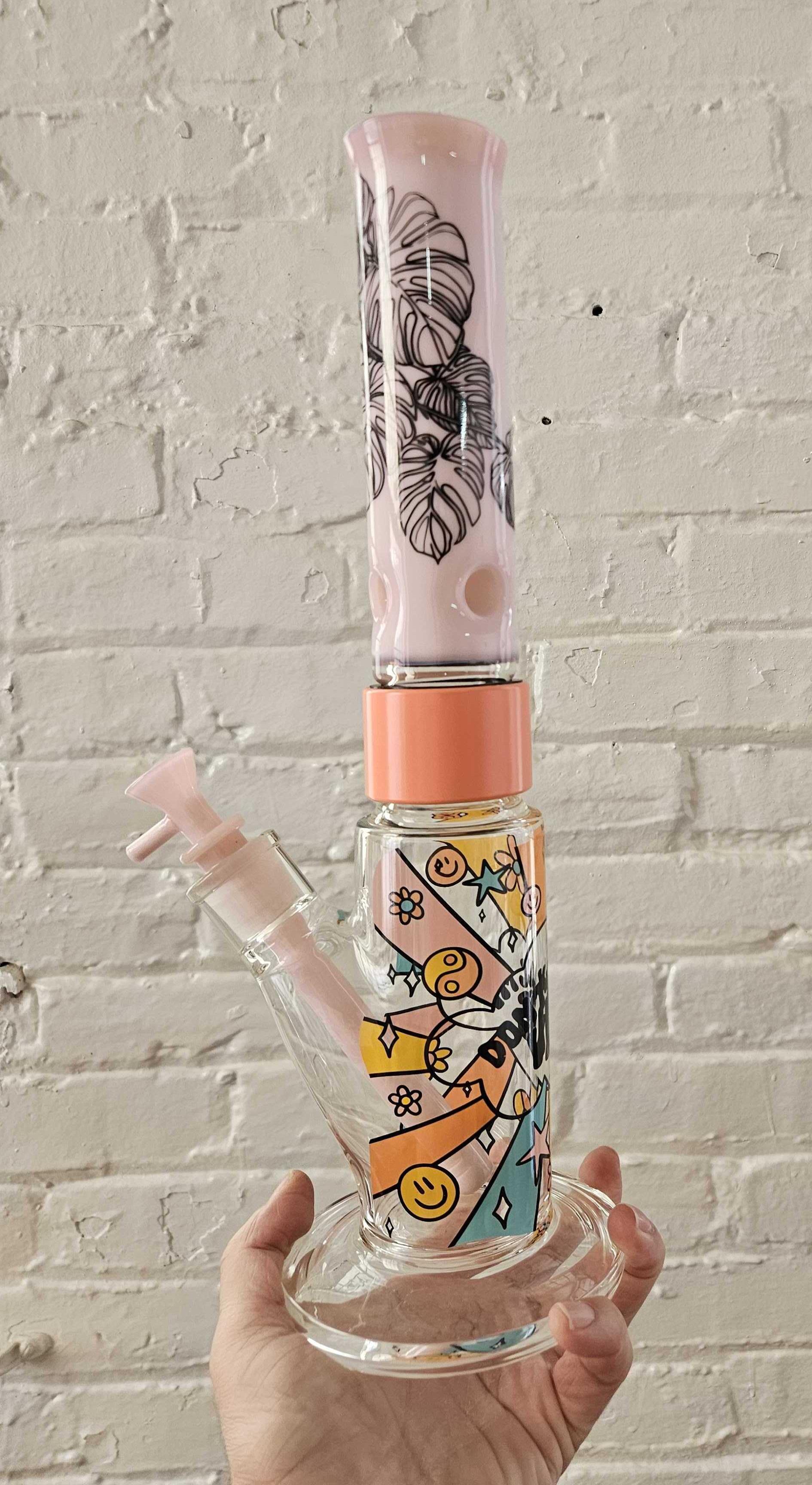 A custom Prism modular bong Single Stack configuration illustrating a "Mix and Match" aesthetic. This setup features a clear Straight Tube base with the Flower Power decal, connected by a Coral Halo to a solid Bubblegum Pink glass mouthpiece with the Monstera decal. Complete with a matching pink downstem and bubblegum bowl.