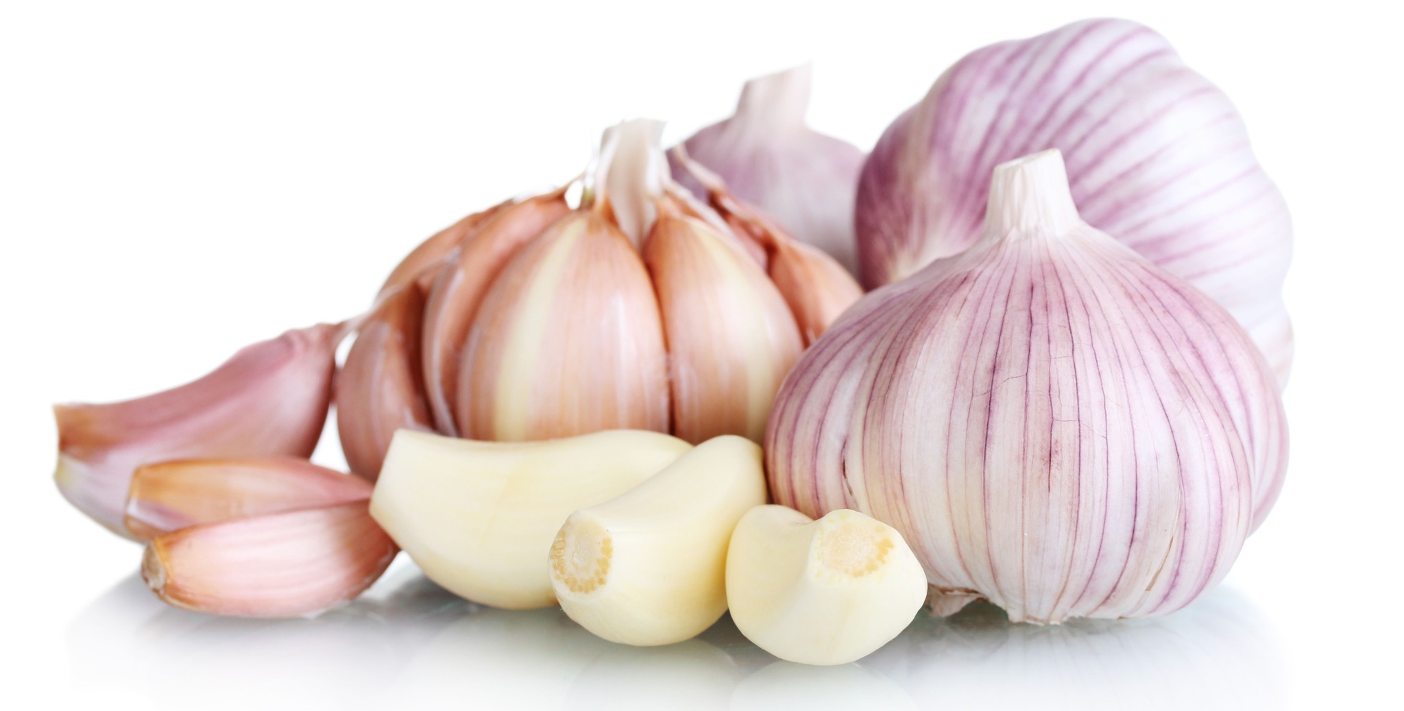 close up on 4 garlic bulbs, 3 unpeeled garlic cloves and 3 peeled garlic cloves.