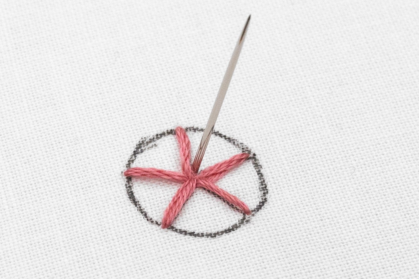 A needle is brought up in the spoke of the woven rose.