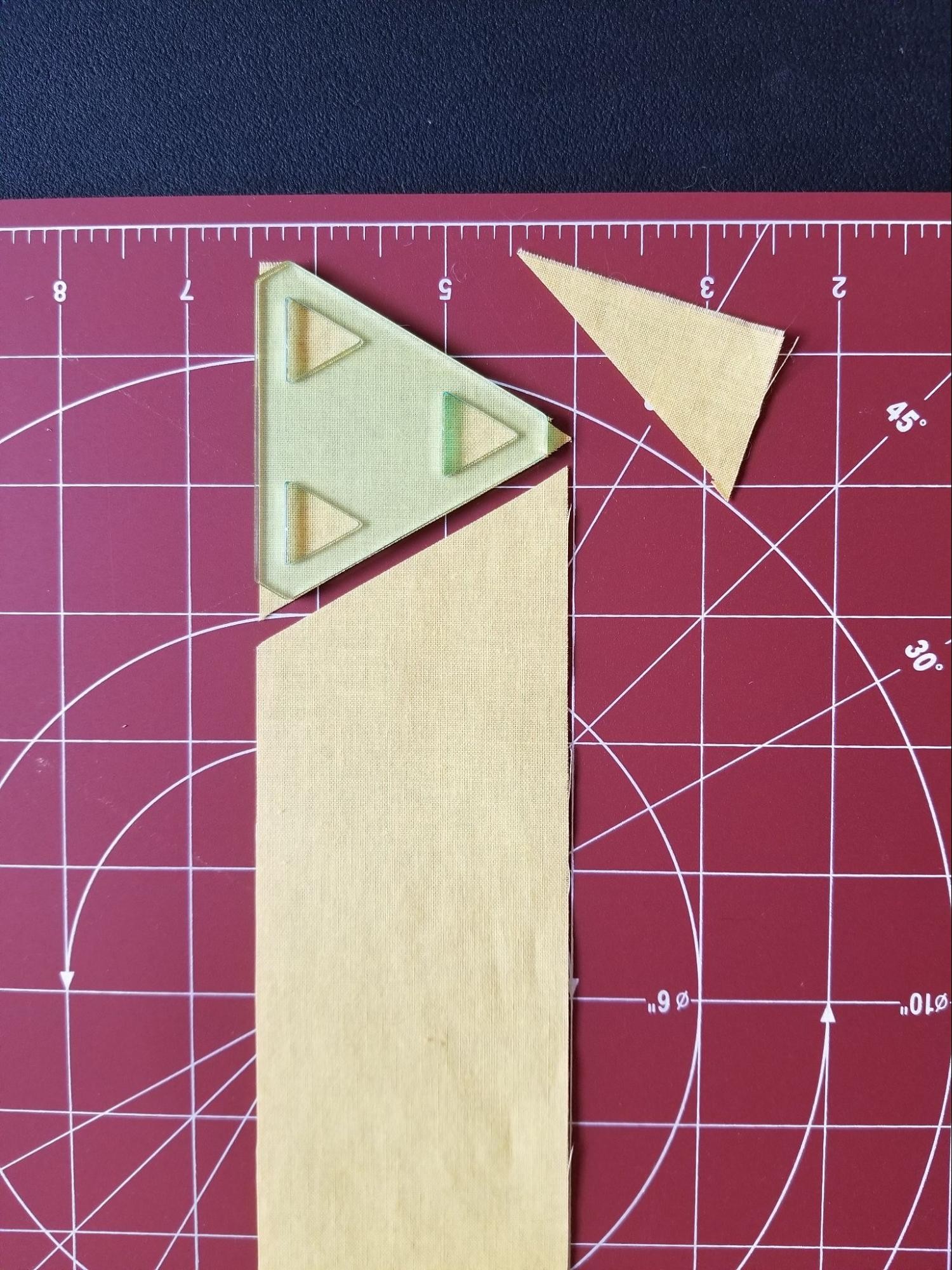 First triangle cut from fabric strip using a 60 degree triangle quilt template.