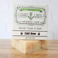Picture of a box of Shart Wash Natural Handmade Bar Soap Cold Brew Coffee scent sitting on a beige bar of soap with a wood background