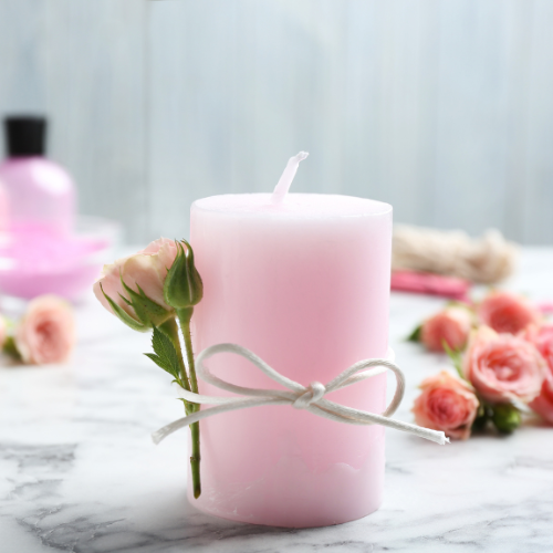 pink candle with a white ribbon and a pink rose.