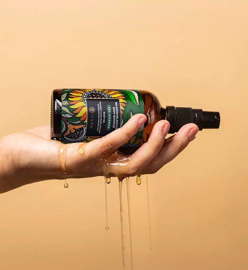 woman holding and Balaayah Black Gram Body Oil being poured from her hand