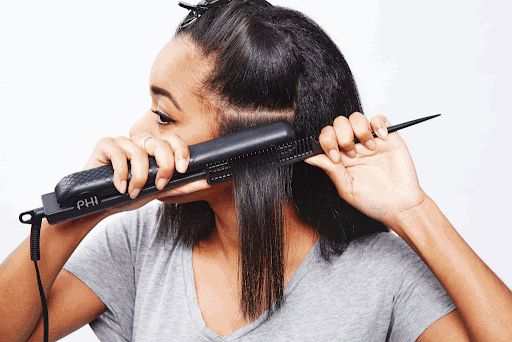 black woman flat ironing her hair with one pass to avoid heat damage