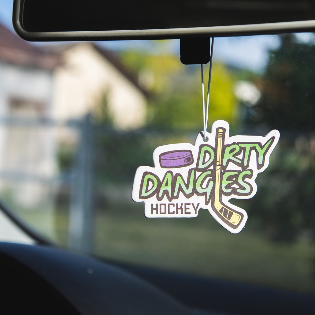 A dirty dangles hockey car air freshener hangs from the rear view mirror of a car