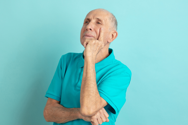 Senior man thinking. Blue background.