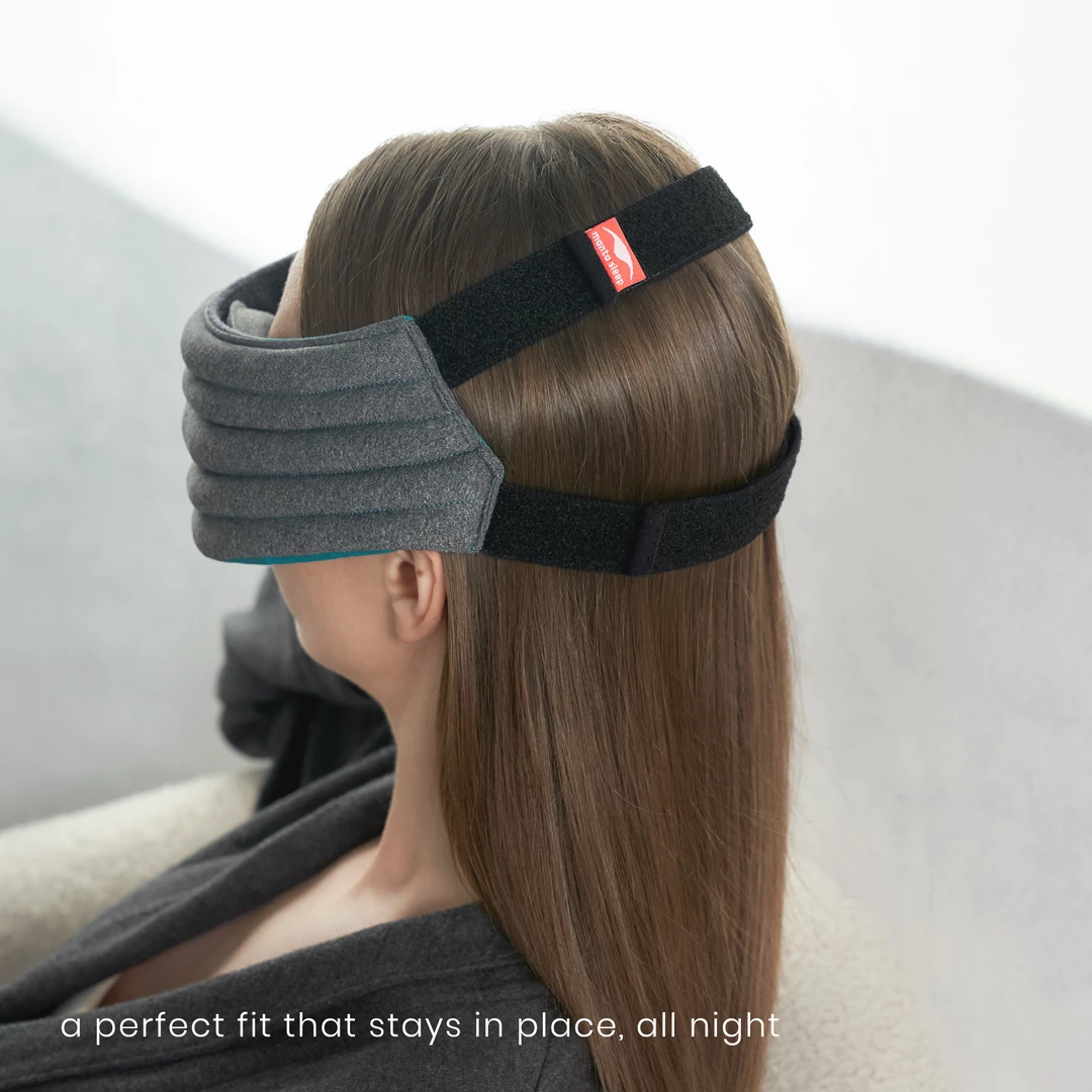 The rear view of the best weighted eye mask for sleep. Two black straps encircle the back of a girl’s head.