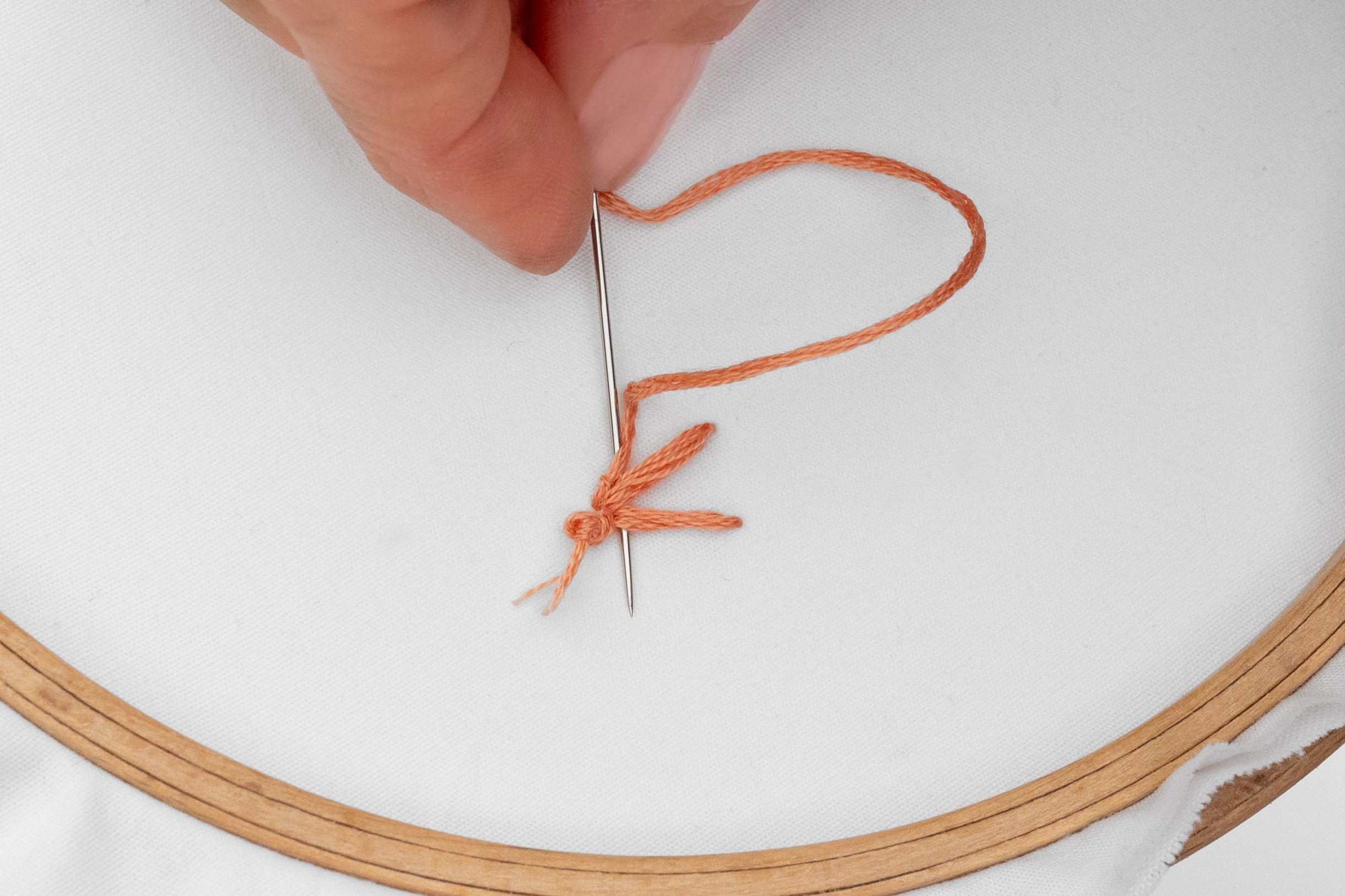 A needle tucks under the back of stitches.