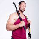 Muscular man in red tank holding XBAR Fitness resistance bar with bands over shoulders for portable strength training