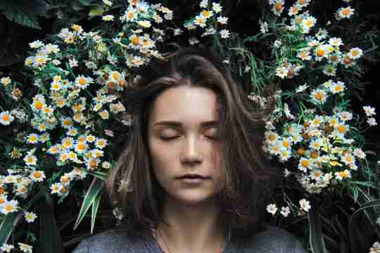 woman in field of daisies representing how diffusing essential oils over night can over stimulate the nervous system 