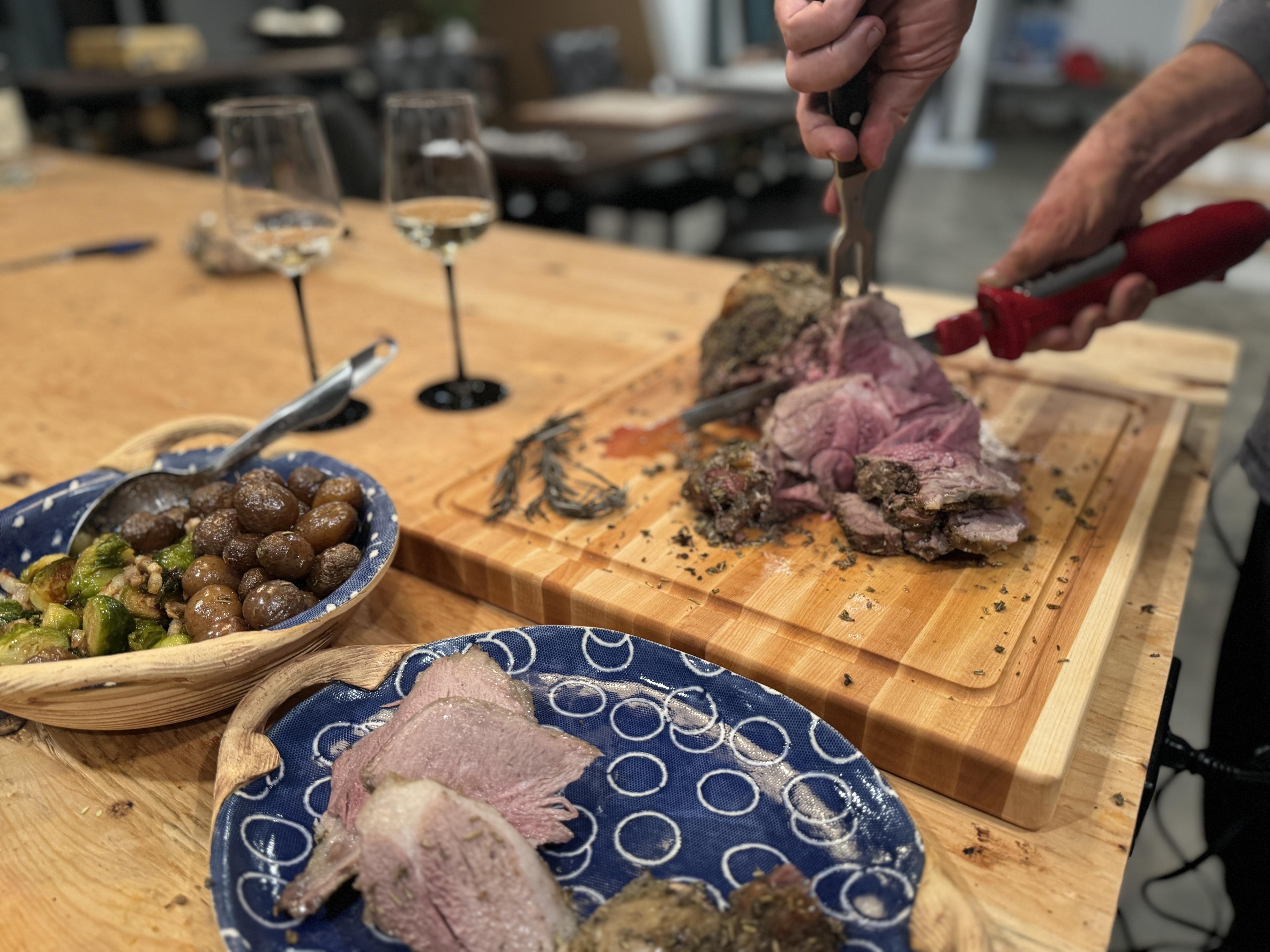 cutting lamb on a roots to table artisan cutting board made of maple.