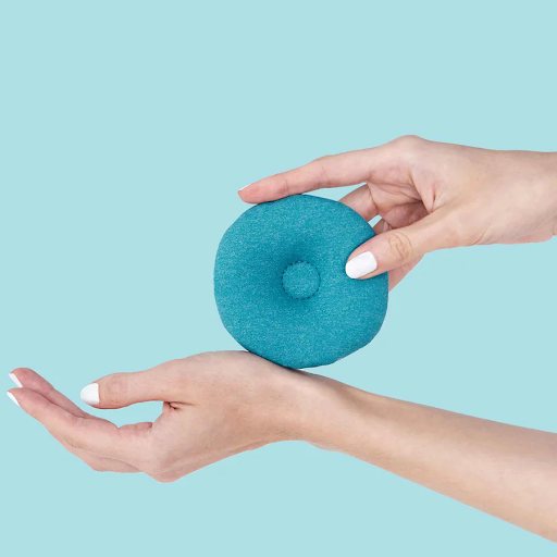 A hand putting a blue circular eye cup on top of the wrist of another hand.