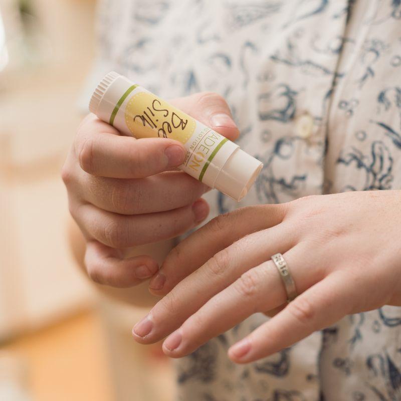 Woman applying Beesilk lotion stick to dry knuckles
