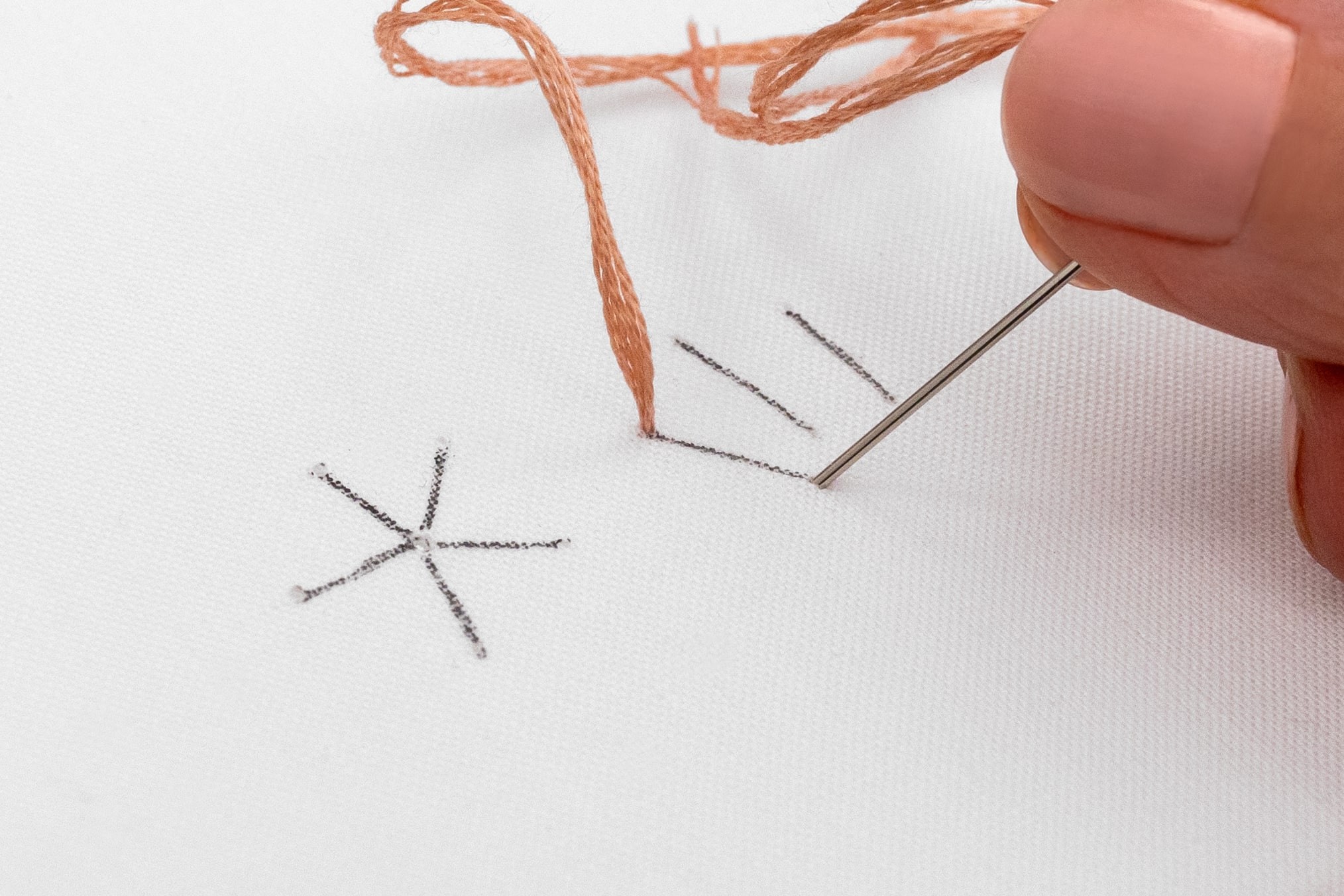 A needle pokes down at the end of a stitch.