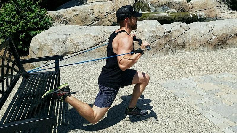 man using resistance band outside on park bench
